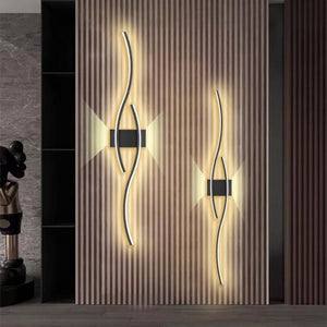 Deux appliques murales noires double courbe LED installées verticalement dans une entrée en bois
