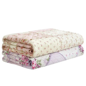 Couvre-lit matelassé plié montrant les coloris rose et violet