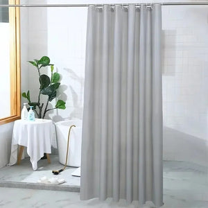Rideau de douche gris installé dans une salle de bain avec baignoire et plante