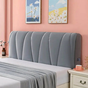 Housse de tête de lit grise capitonnée installée sur un lit dans une chambre chaleureuse