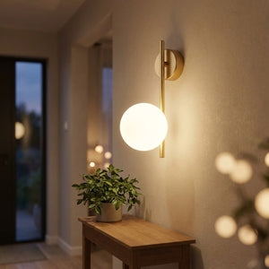Applique murale dorée à globe lumineux dans une entrée chaleureuse