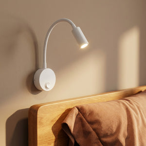 Applique murale liseuse blanche au-dessus d'une tête de lit en bois