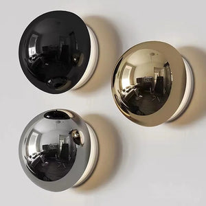 Applique murale ronde disponible en finitions noir argenté et doré avec halo lumineux chaud