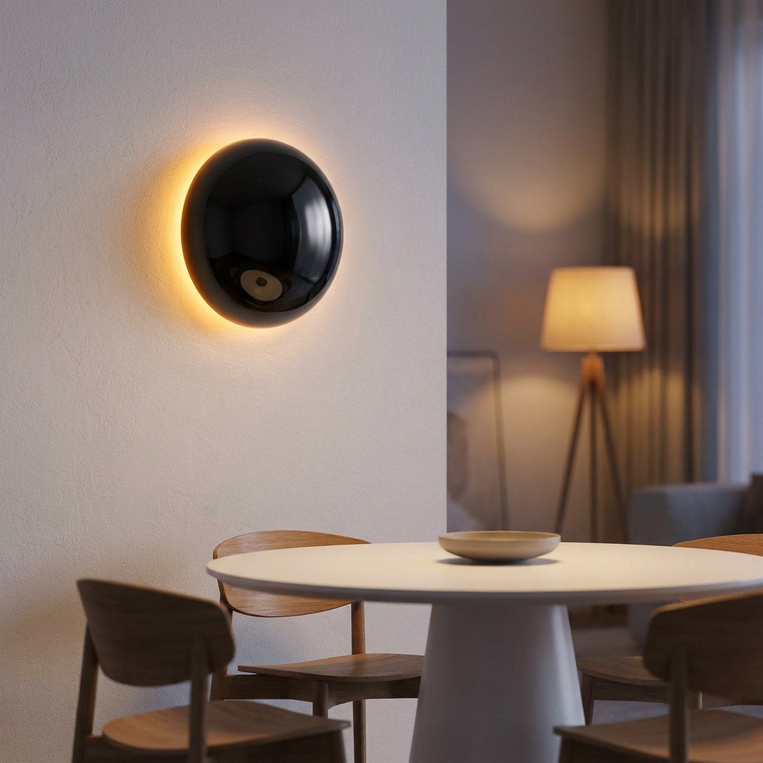Applique murale noire effet éclipse au dessus d'une table à manger ronde en ambiance tamisée
