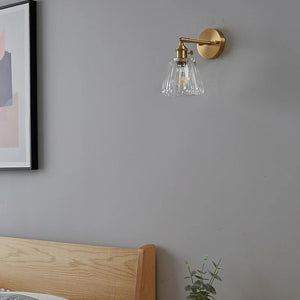 Applique murale en laiton dans une chambre avec cadre et tête de lit en bois