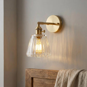 Applique murale dorée en laiton avec globe en verre transparent au-dessus d'une tête de lit
