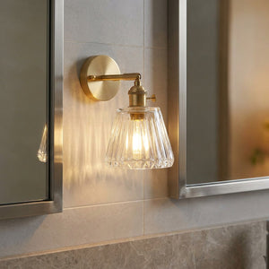 Applique murale en laiton dans une salle de bain avec carrelage gris et miroir