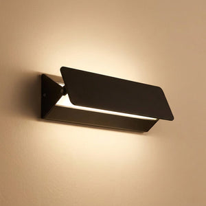 Applique murale LED noire en aluminium diffusant une lumière chaude sur un mur clair
