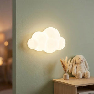 Applique murale nuage allumée sur mur vert sauge près d'une table en bois avec doudou lapin