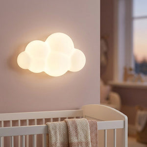 Applique murale nuage allumée dans une chambre de bébé au dessus d'un lit à barreaux