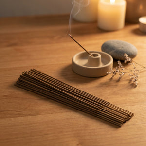 Bâtonnets d'encens naturels posés sur surface en bois avec porte-encens allumé et fumée