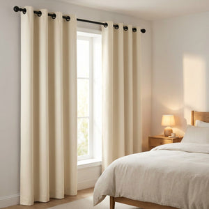 Paire de rideaux occultants beige à œillets encadrant une fenêtre dans une chambre lumineuse