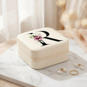 Boîte à bijoux de voyage en cuir PU avec initiale florale posée sur marbre blanc avec lumière naturelle