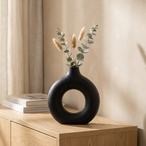 Vase à fleurs anneau noir au design scandinave avec eucalyptus posé sur une console en bois