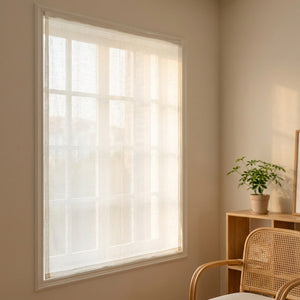 Voilage aspect lin blanc tamisant fixé sans perçage sur une fenêtre lumineuse dans un intérieur chaleureux