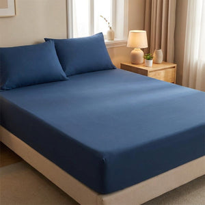 Drap-housse délavé bleu foncé tendu sur un matelas avec oreillers assortis dans une chambre cosy