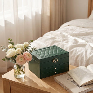 Boîte à bijoux fermée sur table de chevet avec fleurs et livre dans chambre lumineuse