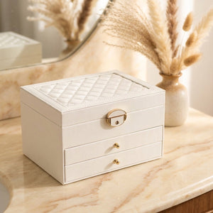 Boîte à bijoux multicouche en cuir blanc crème avec motif matelassé et fermoir doré sur coiffeuse