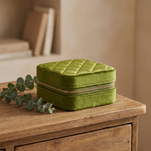 Boîte à bijoux en velours vert olive posée sur une commode en bois