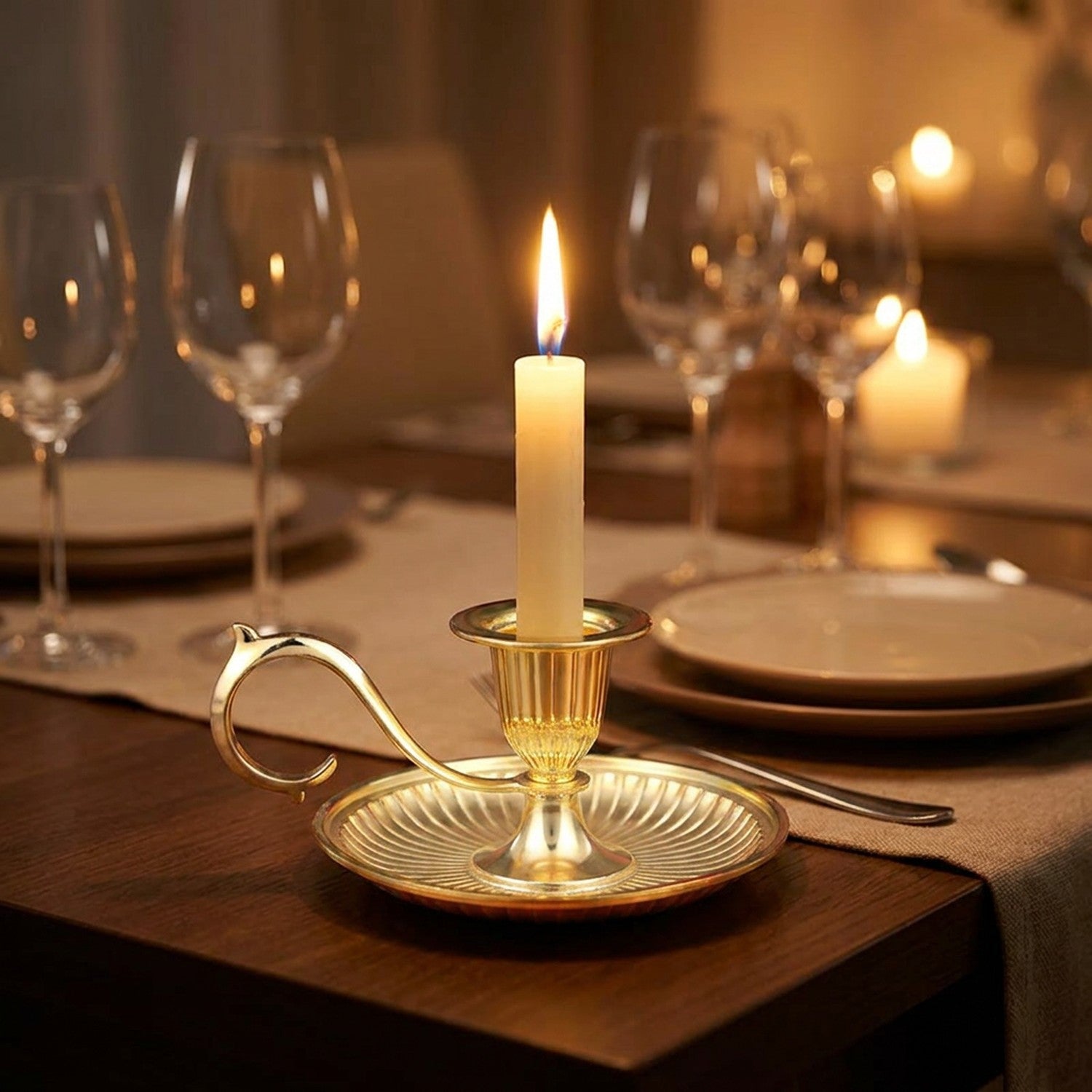 Bougeoir doré avec bougie allumée au centre d'une table dressée pour un dîner romantique