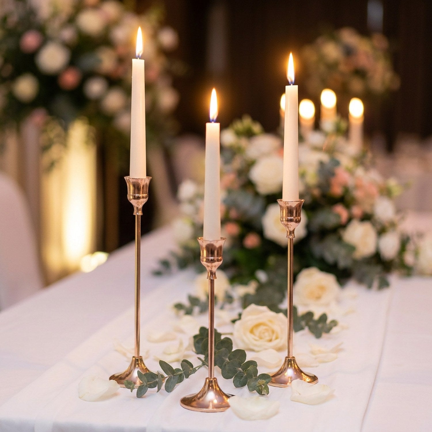 Kit de 3 bougeoirs dorés élancés sur table de mariage avec roses blanches et bougies allumées