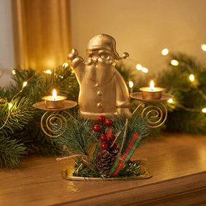 Bougeoir de Noël doré père Noël posé sur une cheminée avec guirlande de pin