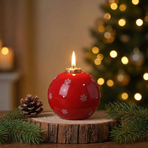 Bougie parfumée de Noël rouge en forme de boule avec flocons de neige allumée sur une table festive