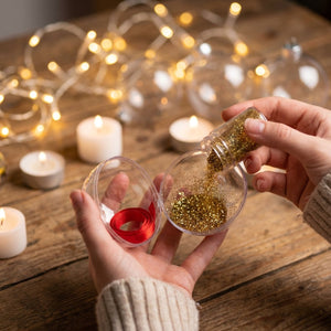 Boule de Noël transparente remplie de paillettes dorées gros plan