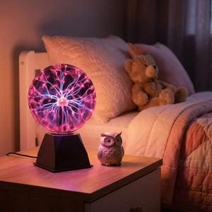 Boule plasma allumée sur une table de chevet dans une chambre d'enfant avec un ours en peluche