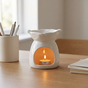 Brûle-parfum céramique blanc allumé sur un bureau avec pot à crayons et carnets