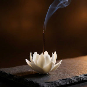 Brûleur d'encens fleur céramique blanche sur surface sombre avec volute d'encens
