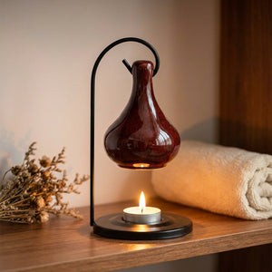 Brûle-parfum en céramique brune suspendu avec bougie allumée