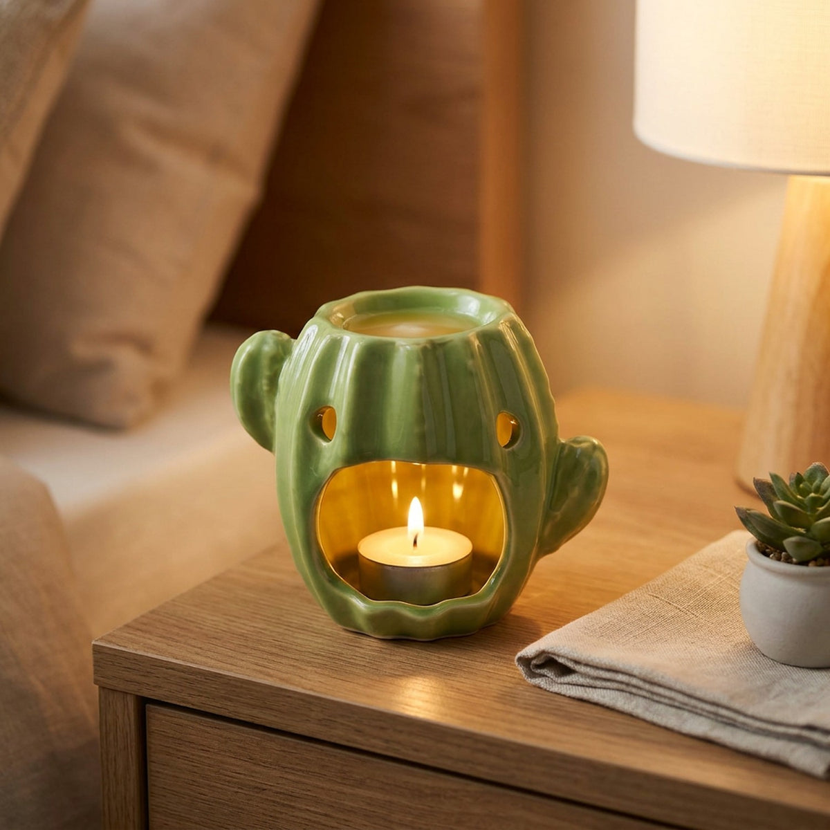 Brûle-parfum cactus en céramique allumé sur une table de chevet