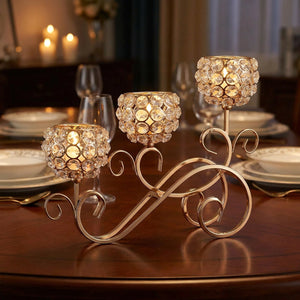 Chandelier 3 branches en cristal doré posé sur une table en bois avec bougies allumées