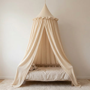Ciel de lit en mousseline de coton beige suspendu au-dessus d'un lit d'enfant