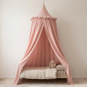 Ciel de lit en mousseline de coton rose suspendu au-dessus d'un lit d'enfant