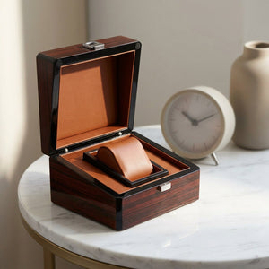 Coffret montre en bois laqué ouvert sur table de nuit en marbre, coussin cuir visible