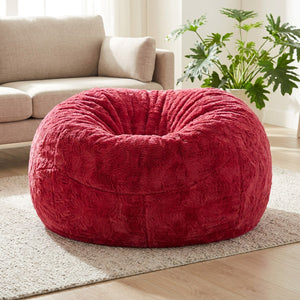 Pouf géant en fausse fourrure rouge posé au sol dans un salon