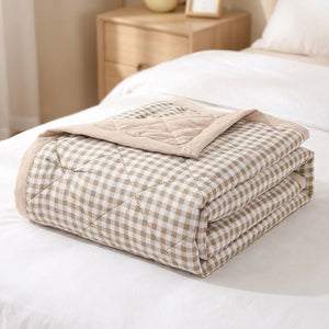 Couette d'été matelassée à petits carreaux vichy beige pliée sur un lit