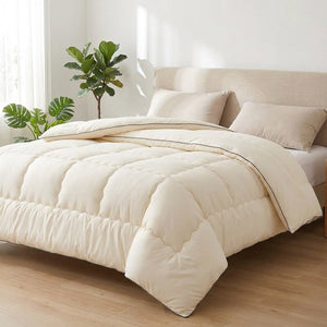 Couette crème déployée comme édredon sur un grand lit dans une chambre lumineuse