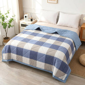 Couette d'été à carreaux bleus dépliée sur un lit fait dans une chambre lumineuse