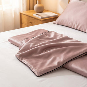 Couette d'été rose poudré en soie posée pliée sur un lit dans une chambre chaleureuse