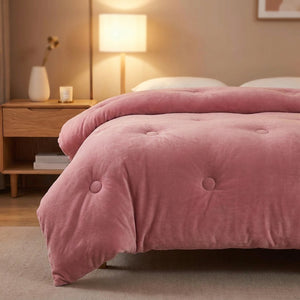 Couette rose poudré en velours de lait matelassée sur un lit dans une chambre cosy