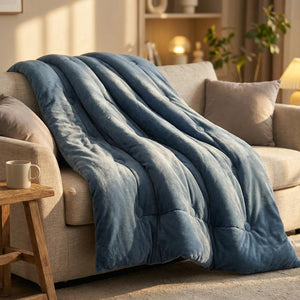 Couette bleue en velours drapée sur un canapé en lin dans un salon chaleureux
