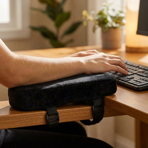 Coussin d'accoudoir en velours utilisé comme repose-poignet sur un bureau devant un clavier