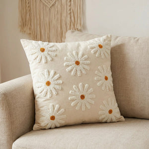 Housse de coussin brodée de fleurs marguerite orange posée sur un canapé beige