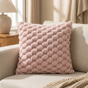 Housse de coussin à pompons de couleur rose sur un canapé