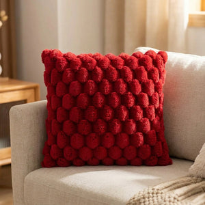 Housse de coussin à pompons de couleur rouge sur un fauteuil