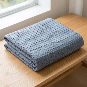 Couverture bambou bleu grise pliée montrant son tissage nid d'abeille
