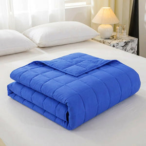 Couverture lestée bleue pliée sur un lit